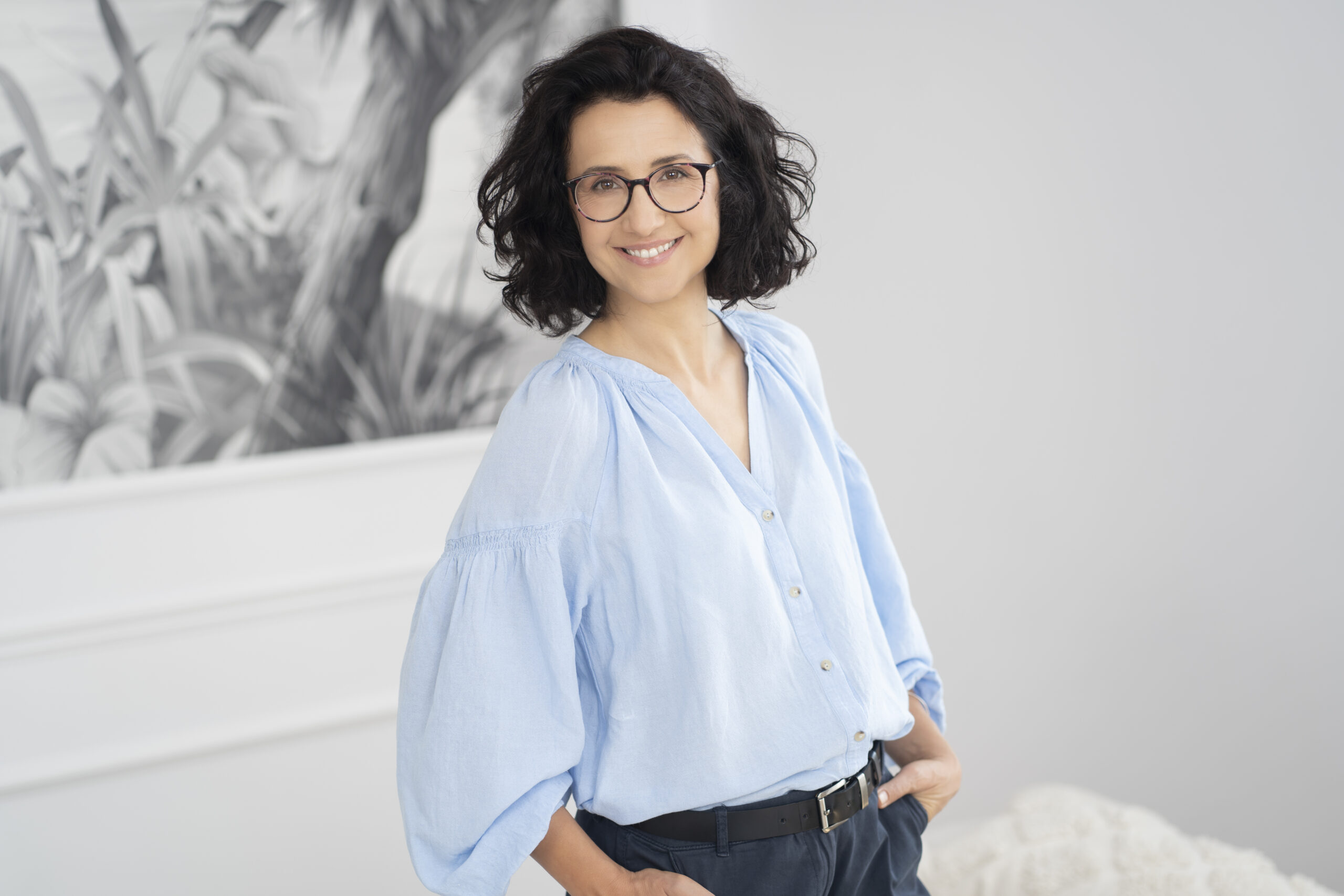 Agnieszka Kaczanowska w niebieskiej bluzce z rękami w kieszeniach